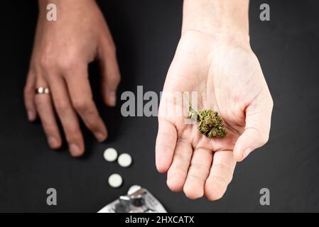 Marihuana und Pillen auf weiblichen Handflächen. Medizinisches Cannabis als Alternative zum Drogenkonzept. Stockfoto