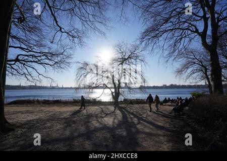 Hamburg, Deutschland. 11. März 2022. Spaziergänger genießen die Nachmittagssonne an der Außenalster. Kredit: Marcus Brandt/dpa/Alamy Live Nachrichten Stockfoto