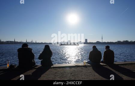 Hamburg, Deutschland. 11. März 2022. Passanten genießen die Nachmittagssonne an der Außenalster. Kredit: Marcus Brandt/dpa/Alamy Live Nachrichten Stockfoto