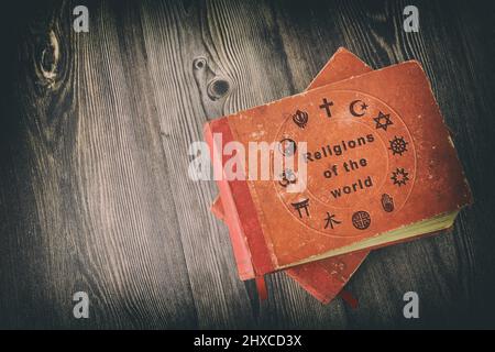 Bücher über das Studium der Weltreligionen mit Einband gedruckt mit religiösen Symbolen auf Holztisch. Stockfoto