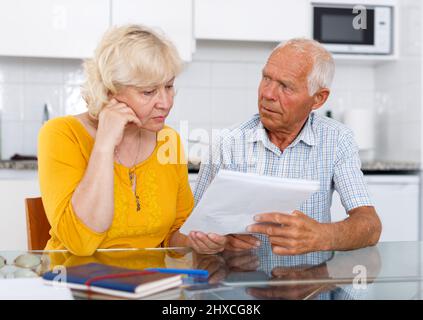 Besorgt reifes Paar mit Dokumenten missbrauchen in zu Hause Stockfoto