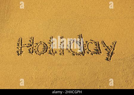 Das Wort Feiertag steht im Sand Stockfoto