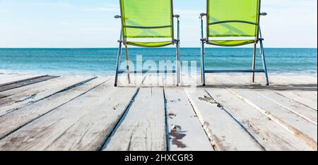 Liegestühle auf einer Holzterrasse am Meer Stockfoto