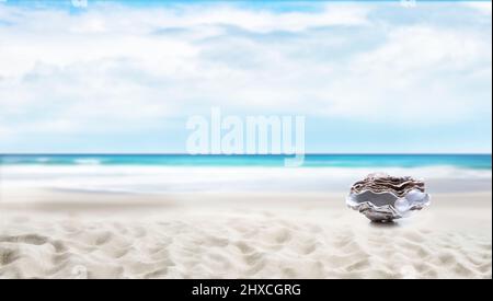 Auster mit Perle am Strand mit Meer im Hintergrund Stockfoto