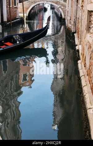 Prow einer venezianischen Gondel in einem kleinen Kanal mit den umliegenden Gebäuden im Wasser reflektiert Stockfoto