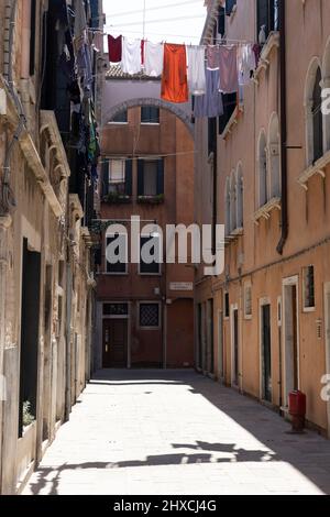 Enge Gasse mit straffer Wäscheleine von Haus zu Haus in Venedig, Italien Stockfoto