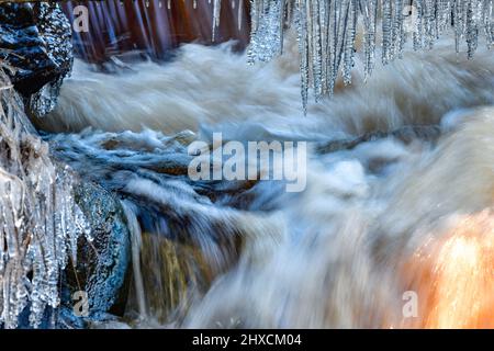 Schnell fließender Bach und Eiszapfen, Torup, Halland, Schweden Stockfoto