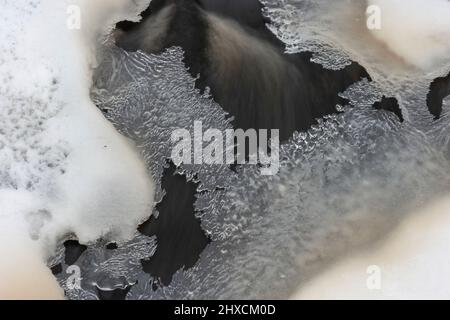 Stream mit schnell fließendem Wasser unter Eiskristallen, Halland, Schweden Stockfoto