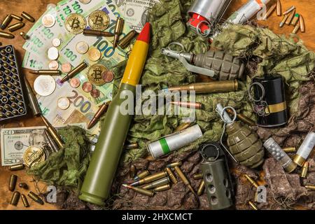 Unterstützung für die Ukraine. Krieg in der Ukraine. Euro-Münzen und -Banknoten und -Patronen verschiedener Kaliber. Verkauf von Waffen. Kriegsmunition Stockfoto