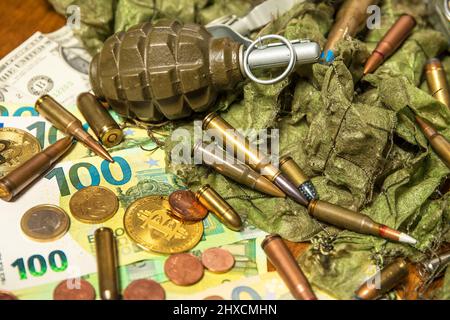 Unterstützung für die Ukraine. Krieg in der Ukraine. Euro-Münzen und -Banknoten und -Patronen verschiedener Kaliber. Verkauf von Waffen. Kriegsmunition Stockfoto