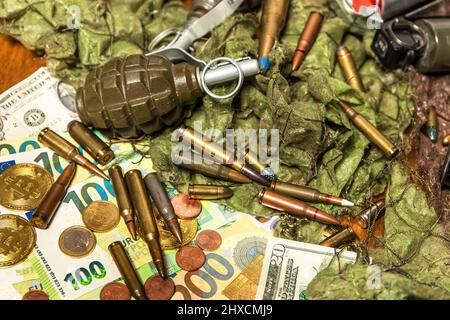 Unterstützung für die Ukraine. Krieg in der Ukraine. Euro-Münzen und -Banknoten und -Patronen verschiedener Kaliber. Verkauf von Waffen. Kriegsmunition Stockfoto