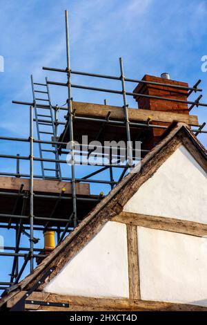 Leitern und Gerüste auf dem Dach eines traditionellen mittelalterlichen Fachwerkgebäudes mit Reparaturarbeiten in England, Großbritannien. Stockfoto