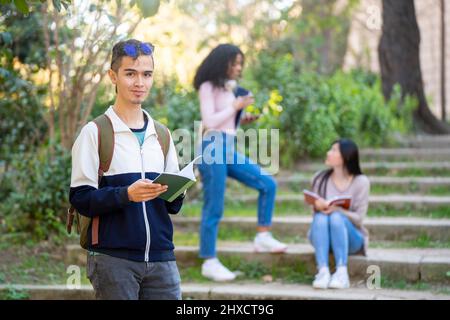 Junge lateinamerikanische Studentin, die lächelt und mit einem Notizbuch zur Kamera schaut Stockfoto