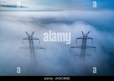 Elektrische Masten an einem nebligen Tag, irgendwo zwischen Tyrnavos und Ambelonas, Larissa, Thessalien, Griechenland. Stockfoto