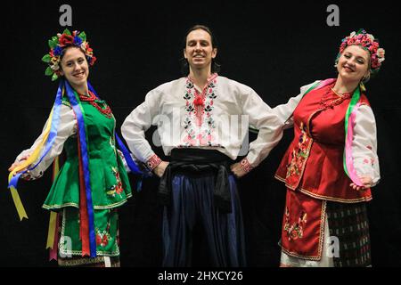 Excel London, Großbritannien. 11. März 2022. Die ukrainische Gruppe Prolisok Dance Ensemble spielt auf der Hauptbühne mit brüllendem Applaus des Publikums und beschaicke mit der von den Organisatoren unterstützten Charity Dance Aid Gelder für die Ukraine. Ivanna Rudnytska, Vicky Varodi und Roman posieren nach der Vorstellung in ihren traditionellen ukrainischen Kostümen. Nach zwei Jahren Abwesenheit ist eine der größten Tanz- und Performance-Shows und -Ausstellungen wieder in vollem Gange und Tausende von Besuchern und Performern besuchen dieses Wochenende die Ausgabe 15. im Excel London. Kredit: Imageplotter/Alamy Live Nachrichten Stockfoto