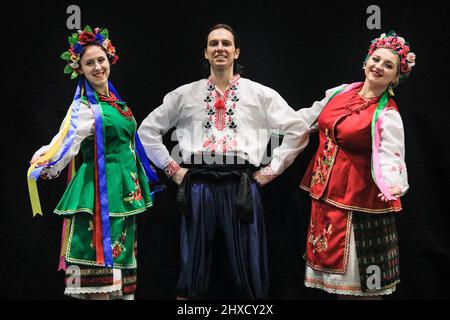 Excel London, Großbritannien. 11. März 2022. Die ukrainische Gruppe Prolisok Dance Ensemble spielt auf der Hauptbühne mit brüllendem Applaus des Publikums und beschaicke mit der von den Organisatoren unterstützten Charity Dance Aid Gelder für die Ukraine. Ivanna Rudnytska, Vicky Varodi und Roman posieren nach der Vorstellung in ihren traditionellen ukrainischen Kostümen. Nach zwei Jahren Abwesenheit ist eine der größten Tanz- und Performance-Shows und -Ausstellungen wieder in vollem Gange und Tausende von Besuchern und Performern besuchen dieses Wochenende die Ausgabe 15. im Excel London. Kredit: Imageplotter/Alamy Live Nachrichten Stockfoto