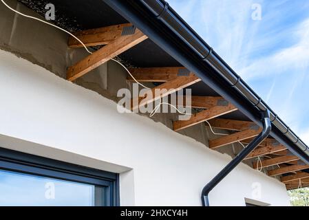 Dachbinder, durch die das Elektrokabel führt, um die Beleuchtung im Soffit zu verbinden. Stockfoto
