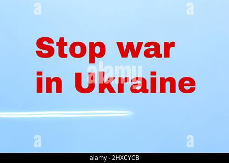Beendet den Krieg in der Ukraine. Inschrift auf einem Hintergrund des blauen Himmels in roten Buchstaben. Spur eines Flugzeugs am Himmel. Russlands Invasion der Ukraine. Stockfoto