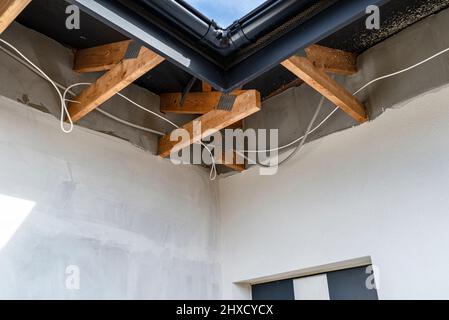 Dachbinder, durch die das Elektrokabel führt, um die Beleuchtung im Soffit zu verbinden. Stockfoto