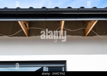 Dachbinder, durch die das Elektrokabel führt, um die Beleuchtung im Soffit zu verbinden. Stockfoto