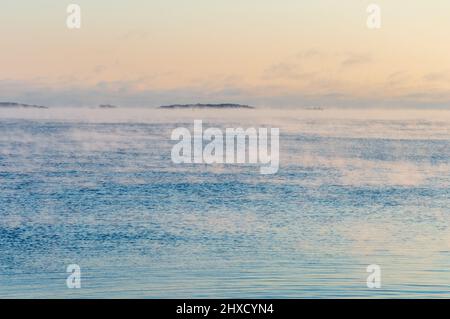 Minimaler Blick auf das Meer von der Küste Helsinkis. Das Wetter ist so kalt, dass das Wasser gefriert und einen leichten Nebel auf seine Oberfläche versprüht Stockfoto