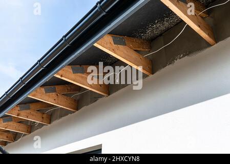 Dachbinder, durch die das Elektrokabel führt, um die Beleuchtung im Soffit zu verbinden. Stockfoto