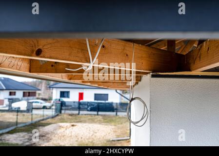 Dachbinder, durch die das Elektrokabel führt, um die Beleuchtung im Soffit zu verbinden. Stockfoto