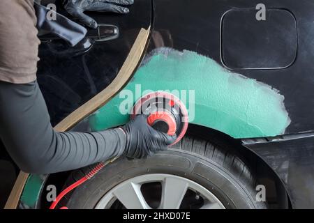 Schleifen von Körperteilen mit einem pneumatischen Mahlwerk vor dem Lackieren. Stockfoto