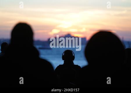 Hamburg, Deutschland. 11. März 2022. Passanten genießen den Sonnenuntergang im Hafengebiet an der Elbe im Hamburger Hafen. Kredit: Marcus Brandt/dpa/Alamy Live Nachrichten Stockfoto