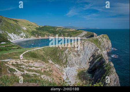 Eine Sommer-Tagesansicht von Lulworth Cove von den Hügeln über Stair Hole, die die verdrehten Felsformationen zeigt. Teil der Dorset Jurassic Küste. Stockfoto