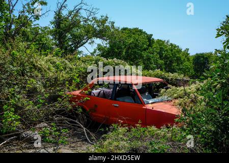 Theologos, Thassos, Griechenland - im Bergdorf Theologos auf der Insel Thassos steht in der Landschaft ein alter, rostroter Schrottwagen, der langsam von Pflanzen bewachsen wird. Stockfoto