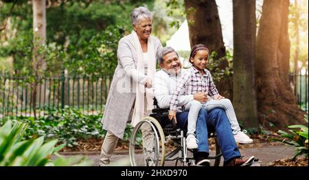 Eine Fahrt durch den Park. Aufnahme eines entzückenden kleinen Mädchens, das mit ihren Großeltern im Park spielt. Stockfoto