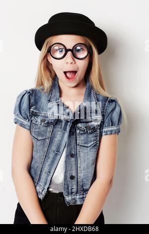 Ein Gesicht ziehen. Porträt eines jungen Mädchens mit großen runden Gläsern, das im Studio posiert. Stockfoto