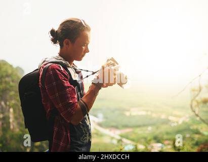 Nichts kann Erfahrung ersetzen. Ausgeschnittene Aufnahme eines jungen Touristen, der im Urlaub Fotos macht. Stockfoto