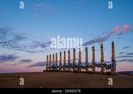 Buntes Klebeband auf den Holzsäulen im heiligen burjat Platz auf Kap Burkhan im Dorf Khuzhir auf der Insel Olchon im Sonnenuntergang Stockfoto