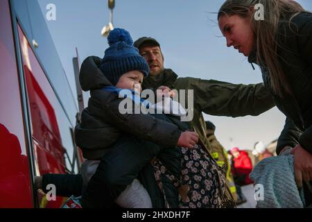 Medyka, Polen. 11. März 2022. Ukrainische Flüchtlingsfamilie mit einem Kind, das in einem Bus ansteht, der Flüchtlinge nach Przemysl bringt. Ukrainische Flüchtlinge am Grenzübergang Medyka am 16.. Tag der russischen Invasion in der Ukraine. Kredit: SOPA Images Limited/Alamy Live Nachrichten Stockfoto