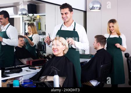 Professionelle Stylistin schneiden Haare von älteren Blondine Stockfoto