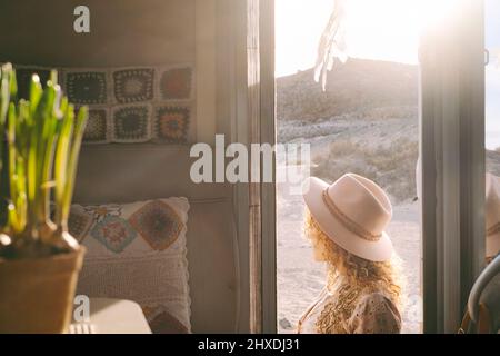 Innenansicht der Reisenden Frau genießen Sonnenuntergang Zeit auf dem Wohnmobil rv Tür. Reisen und Fernweh Lifestyle modernes, trendiges People-Konzept. Weiblicher Witz Stockfoto