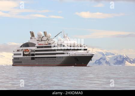 Das Ponant-Kreuzschiff Le Boreal hält in der Wilhelmina-Bucht in der Antarktis seinen Platz, während die Passagiere in Tierkreisbooten Sightseeing-Touren Unternehmen. Stockfoto