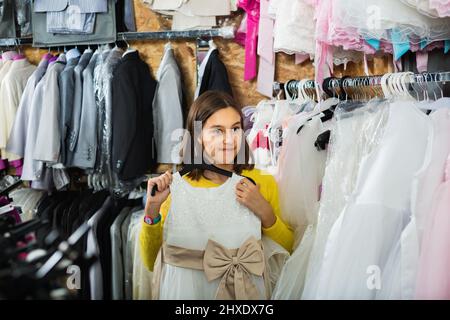 Teenager-Kunde prüft Kleider im Kinderkleidergeschäft Stockfoto