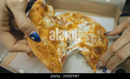 Mädchen essen Pizza Käse vier. Nahaufnahme von jungen Frau Mund gierig essen Pizza und Kauen im Restaurant im Freien. Menschliche Hände nehmen Stücke Scheiben von Stockfoto