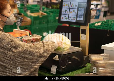 Frau, die Bananen in einer Plastiktüte auf der Supermarktwaage wiegt Selective Focus Stockfoto