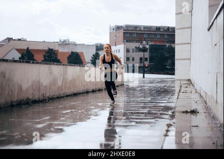 Junge sportliche Frau beim Joggen in der Stadt. Running Fitness Mädchen in Sportswear im Freien. Stockfoto