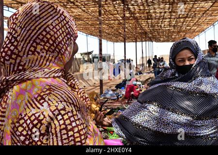 Agadez, Niger. 27.. Februar 2022. Maribel Seegmiller (rechts), 724. 27 2022 Expeditionary Air Base Squadron Director of Operations, probiert während eines Basars auf dem Nigerien Air Base 201, Agadez, Niger, ein traditionelles afrikanisches Kleid an. Über 40 lokale Händler aus der Stadt Agadez und den umliegenden Dörfern besuchten den Basar und verkauften verschiedene Waren. US-Servicemitglieder kauften Waren im Wert von rund 10.532.000 westafrikanischen CFA-Francs (18K USD). Solche Ereignisse stärken die Beziehungen zwischen den USA und Niger und stimulieren die lokale wirtschaftliche Entwicklung. (Bild: © U.S. Stockfoto