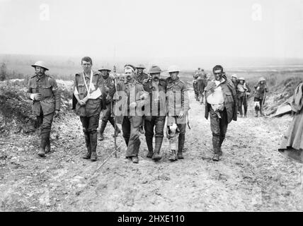 Ein deutscher Gefangener hilft britischen Verwundeten, nach Kämpfen am Bazentin Ridge am 19. Juli 1916 während der Schlacht an der Somme, auf den Weg zu einer Umkleidekabine in der Nähe von Bernafay Wood zu gelangen. Stockfoto