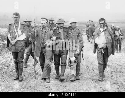 Ein deutscher Gefangener hilft britischen Verwundeten, nach Kämpfen am Bazentin Ridge am 19. Juli 1916 während der Schlacht an der Somme, auf den Weg zu einer Umkleidekabine in der Nähe von Bernafay Wood zu gelangen. Stockfoto