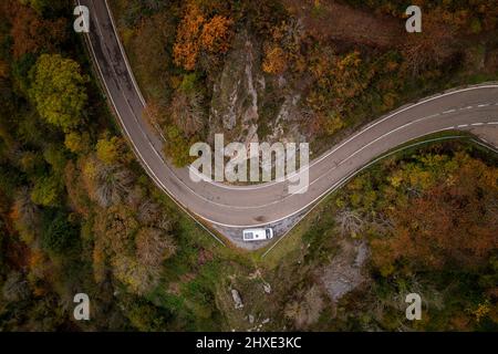 Drohnenansicht eines Wohnwagens mit Sonnenkollektoren auf einer Straße in einer Berglandschaft im Herbst Stockfoto