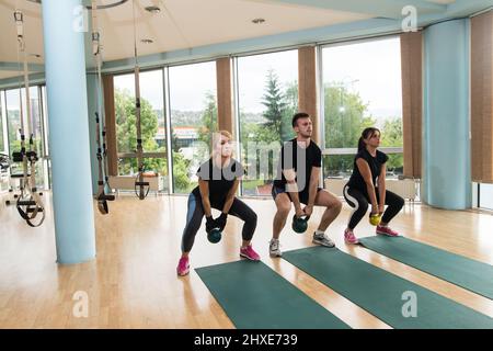 Fitness Gruppe von Menschen, die Powerlift-Übungen mit Kettlebells in einem Fitnessstudio Stockfoto
