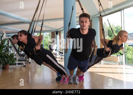 Attraktives Team-Training mit Fitness TRX-Trägern im Fitnessstudio Stockfoto