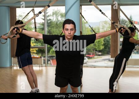 Attraktives Team-Training mit Fitness TRX-Trägern im Fitnessstudio Stockfoto